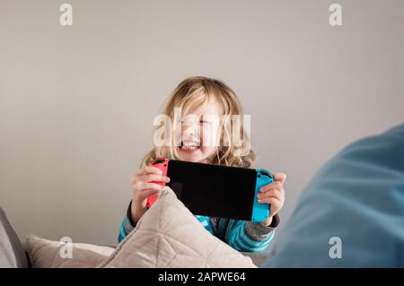 young girl pulling faces whilst playing Nintendo switch at home Stock Photo