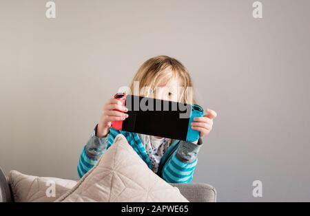 young girl playing Nintendo switch at home on the sofa Stock Photo