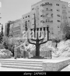 Israel 1964-1965: Jerusalem (Jerusalem), street images  Man cleans the 5 meter high menora with a water hose, seen from the opposite Knesset (parliament building) Annotation: A menora is a seven-armed candlestick and the ancient symbol for the Hebrew people (also it is one of the oldest symbols for Judaism in general) Date: 1964 Location: Israel, Jerusalem Keywords: apartment buildings, candlestick, cleaning, street sculptures, water snake Stock Photo