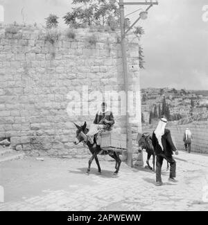 Israel: Nazareth  Man riding on loaded donkey passes a pedestrian Date: undated Location: Galilee, Israel, Nazareth Keywords: donkeys, street images, means of transport, pedestrian Stock Photo