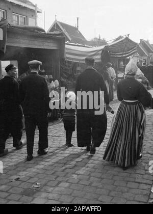 Costume in the Netherlands  Men, woman and child walking along the fair in Volendam in traditional costume Date: september 1934 Location: Noord-Holland, Volendam Keywords: fairgrounds, costume Stock Photo