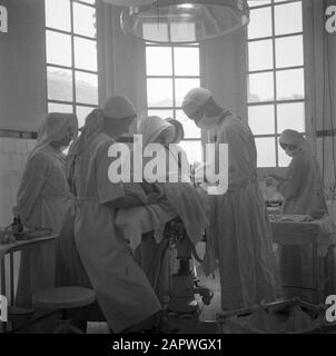 War volunteers in Malacca and Indonesia  Medical operation in Bandoeng Annotation: Published in the book: 'The guys of the ded' with the caption: 'where needed, surgical intervention in the hospitals ingest' Date: 1 April 1946 Location: Bandung, Indonesia, Dutch East Indies Keywords: surgeons, operating rooms, operations, nurses, hospitals Stock Photo
