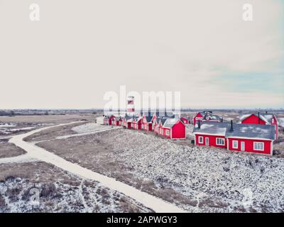 Wooden red houses of fishing village in snowy covered in winter. Stylish and modern fishing village from a bird's eye view. A few red houses near the Stock Photo