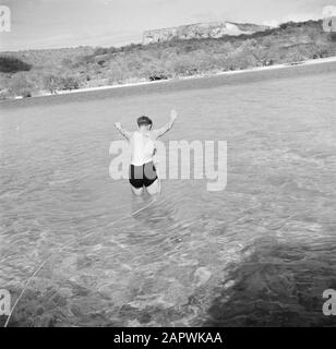 Journey to Suriname and the Netherlands Antilles  Military on a rope enters the water of the Fuik Bay on a military patrol. In the background the Table Mountain Date: 1947 Location: Curaçao Keywords: military, beaches, swimming Stock Photo