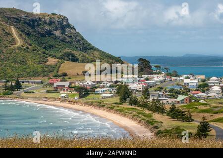 Stanley, Tasmania, Australia - December 15, 2009: The town at the base of The Nut volcanic plug. Beach and surf. Cloudscape and blue ocean with mounta Stock Photo