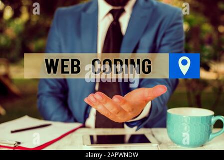 Writing note showing Web Coding. Business concept for work involved in developing a web site for the Internet Man in front of table. Mobile phone and Stock Photo