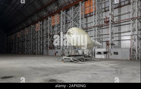 Small blimp on a mooring platform inside empty big airship hangar Stock Photo