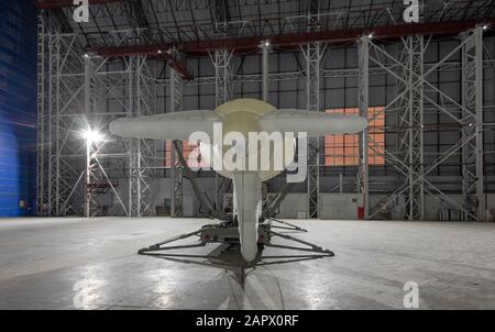 Small blimp on a mooring platform in a giant aircraft hangar. View from the back Stock Photo