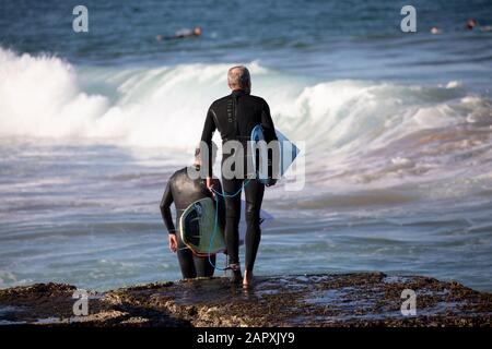 Sydney, middle aged male surfers head to the ocean at Avalon Beach Sydney for a surf,Australia Stock Photo