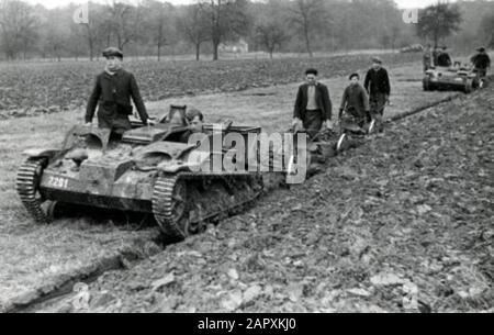 Spaarnestad Photo/SFA022804385 World War II. German soldiers in tankette help French farmers on land with plowing. France, 1941. Tankette: small tank exploited by Germans (Renault) which was used for various activities. Second World War. German soldiers in tankette (little tank) are helping French farmers plough their fields. France, 1941. [Tankette: little tank (Renault), captured by German forces and used for various tasks]. Stock Photo