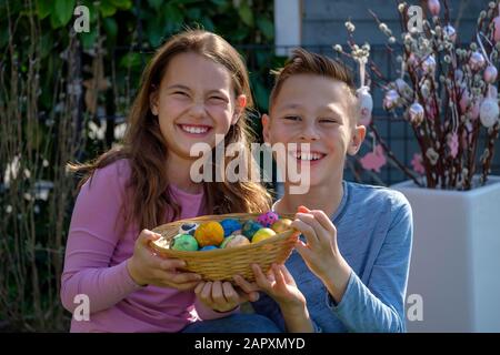 Siblings, girls and boys are happy about baskets with painted Easter eggs, Bavaria, Germany Stock Photo