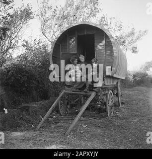 Tinkers in Ireland  Woman with children on the goat of a covered wagon Annotation: 'Tinker' is the English word for ketellapper Date: January 1, 1930 Location: Ireland Keywords: families, covered cars, Gypsies Stock Photo