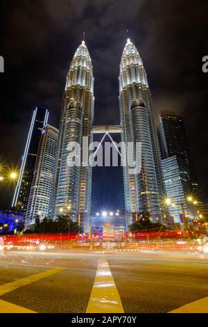 KUALA LUMPUR, MALAYSIA - JANJUARY 12 ,2020 : Close up of KLCC Petronas Twin Tower at night from low angle by the roadside with light trail. Stock Photo