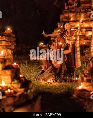 Thai dancing girl in Ayutthaya style dress with candle at night Stock Photo