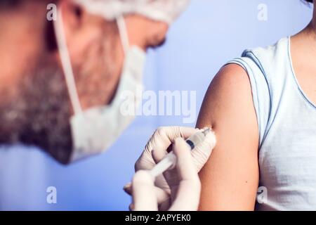 A doctor doing injection to the patient in medical office. Isolated. Close up shot. Medicine and healthcare concept Stock Photo