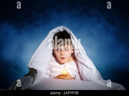 Surprised child hiding under blanket Stock Photo