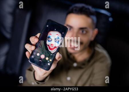 Hand of young smiling man holding smartphone while using multimedia application Stock Photo