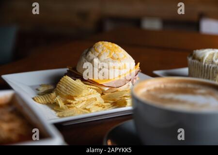 Ham sandwich with potato chips sitting on a dining table. Stock Photo
