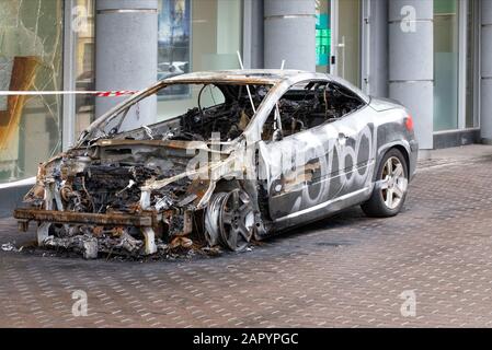 A burned-out car stands on the sidewalk of a city street, side view of a burned-out passenger compartment, image with copy space. Stock Photo