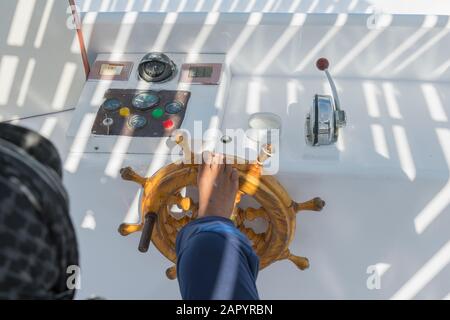 People at the helm of a white yacht. A man Arab controls the yacht. Foot on the yacht steering wheel. Stock Photo