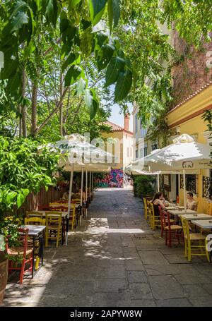 Tree framed street with traditional Greek Taverna tables and chairs in the streets of old Plaka, Athens, Greece Stock Photo