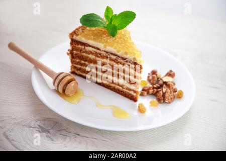Honey cake with golden pearls and mint leaf and cinnamon on stone plate isolated on white background Stock Photo