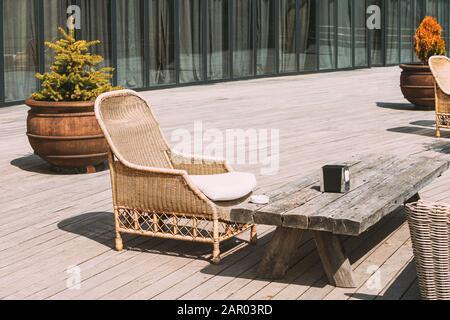 Wicker Furniture On Balcony At Sunny Summer Day. Home Exterior With Chair And Wooden Table In A Wooden Terrace. Stock Photo