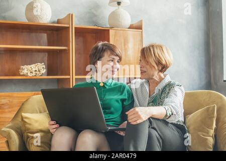 Happy mature women chatting and using laptop at home Stock Photo