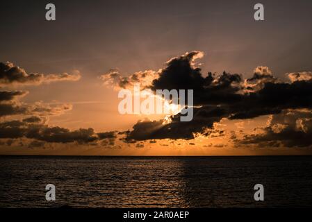 Sunset over the ocean with big clouds in front of the sun Stock Photo