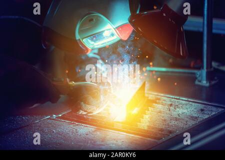 Industrial welder worker is welding metal part in factory with protective mask welding metal Stock Photo