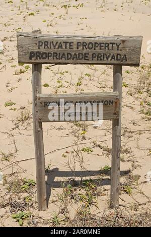 Private property sign on the beach with gullfeed (Scaevola plumieri), Ponta Malongane, Mozambique. Stock Photo