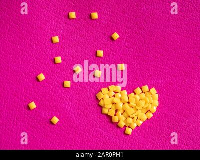 Yellow crystal craft handmade heart shape for diamond embroidery hobby rhinestone. Background with bright leather texture. Pink piece of natural tanne Stock Photo