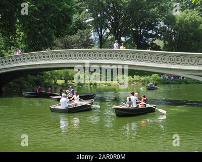New York, USA - June 2, 2019: People rowing under the Bow Bridge in Central Park. Stock Photo