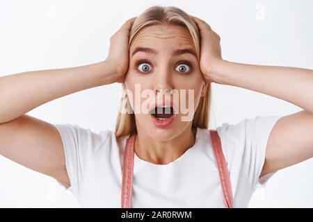 Close-up of panicking, shocked young attractive blond girl with blue eyes, tattoo, gasping drop jaw staring concerned and upset with terrible news Stock Photo