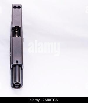 A black 9mm semi automatic pistol with an opened slide showing a bullet in the magazine on a white background with copy space Stock Photo