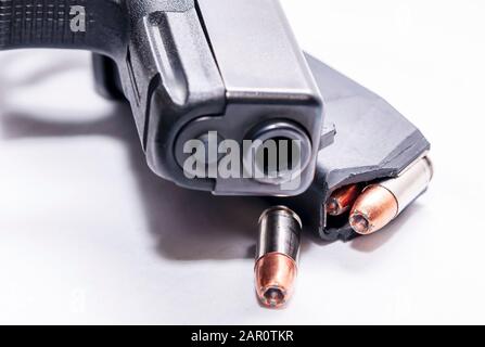 A black 9mm semi automatic pistol with a loaded pistol magazine with a single 9mm hollow point bullet on a white background Stock Photo