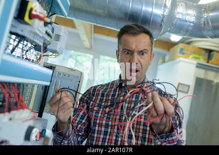 electrician trying to untangle wires in repair concept Stock Photo