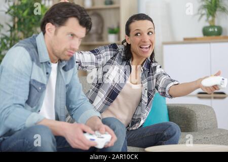 woman beating her boyfriend while playing video games Stock Photo
