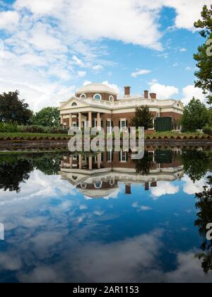 Beautiful Jefferson Monticello mansion reflecting in pool with clouds hanging above on sunny day. Reflection in calm lake mirroring landmark plantatio Stock Photo