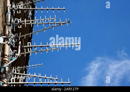array of television aerials on the wall of a tenement block in scotland against a blue sky Stock Photo