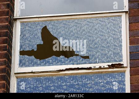 broken window in an old abandoned 1960s office building England UK Stock Photo