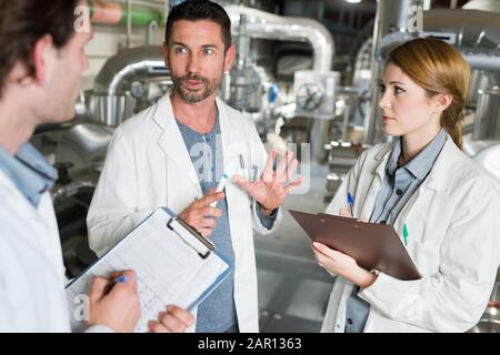 three technicians in discussion holding clipboards Stock Photo