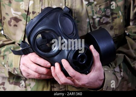 man in combat fatigues holding gas mask Stock Photo