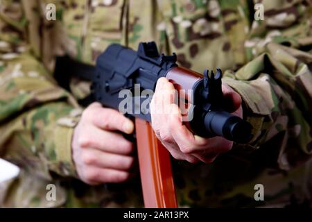 man in combat fatigues holding aks-47u close quarter combat kalasknikov rifle holding in threatening position stance defending Stock Photo