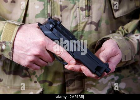 man in combat fatigues holding automatic pistol Stock Photo