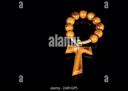 Tau, wooden cross in shape of the letter t (religious symbol of St. Francis of Assisi) with rosary bead, on black background with reflections Stock Photo