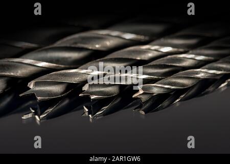 Extreme close-up of black and grey drill tips on a dark background with reflections Stock Photo