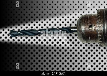 Extreme close-up of an electric drill with black tip on a white background with many black holes of different diameters Stock Photo