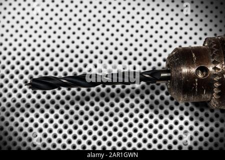 Extreme close-up of an electric drill with black tip on a white background with many black holes of different diameters Stock Photo