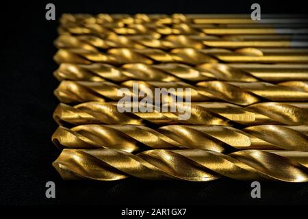 Extreme close-up of a set of golden drill tips on a black background, selective focus Stock Photo